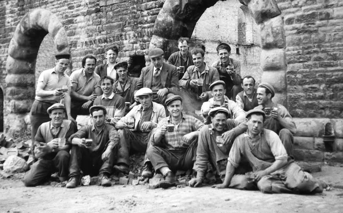 The Marble Mosaic Company factory manager Peter Maddalena can be seen in the centre of this image along with other factory employees. This photo was taken while rubble was being cleared after the buildings height was reduced. This photo is taken in front of the eastern warehouse. Image dated 1959/1960.